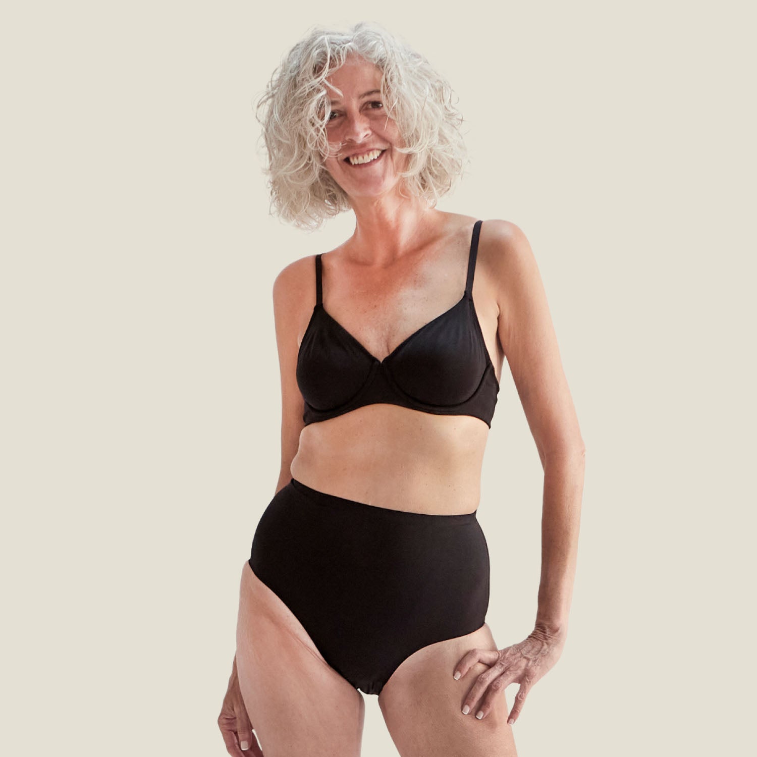 Woman smiling and wearing the Drytech™ High Waist Incontinence Brief in black, designed for light leaks with a comfortable and secure fit.