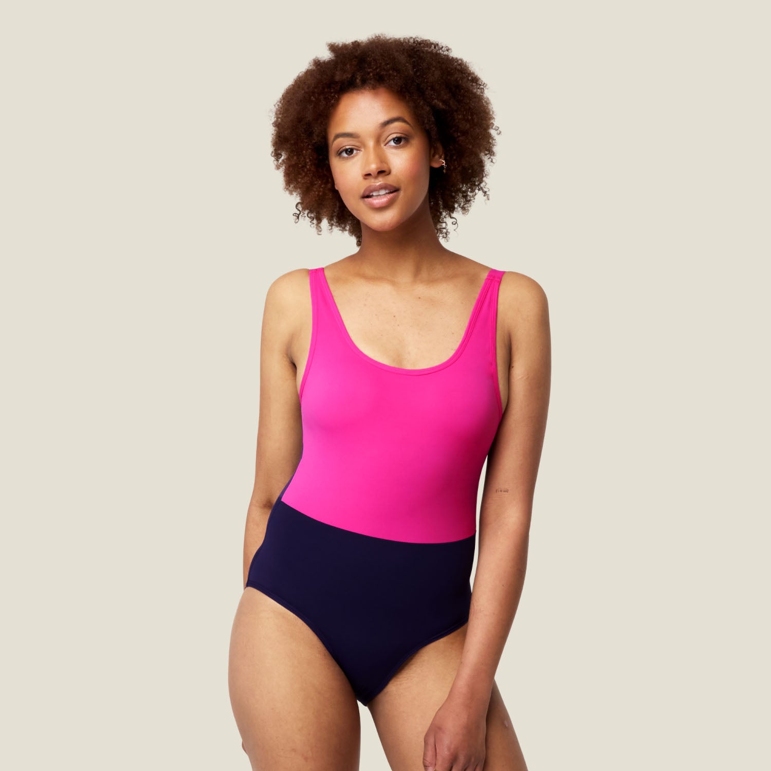 Model wearing WUKA Period Scoopback Swimsuit in vibrant pink and purple, designed for medium flow period protection, full-length front view.